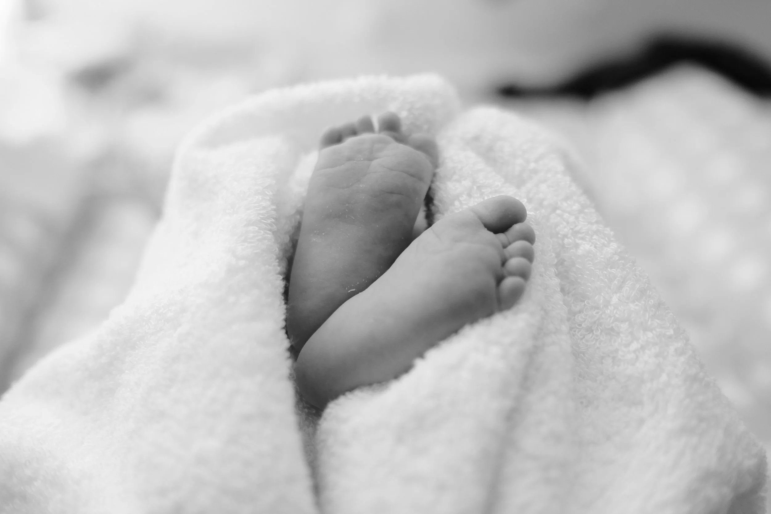 Black-and-white close-up of a baby's feet resting on a soft towel