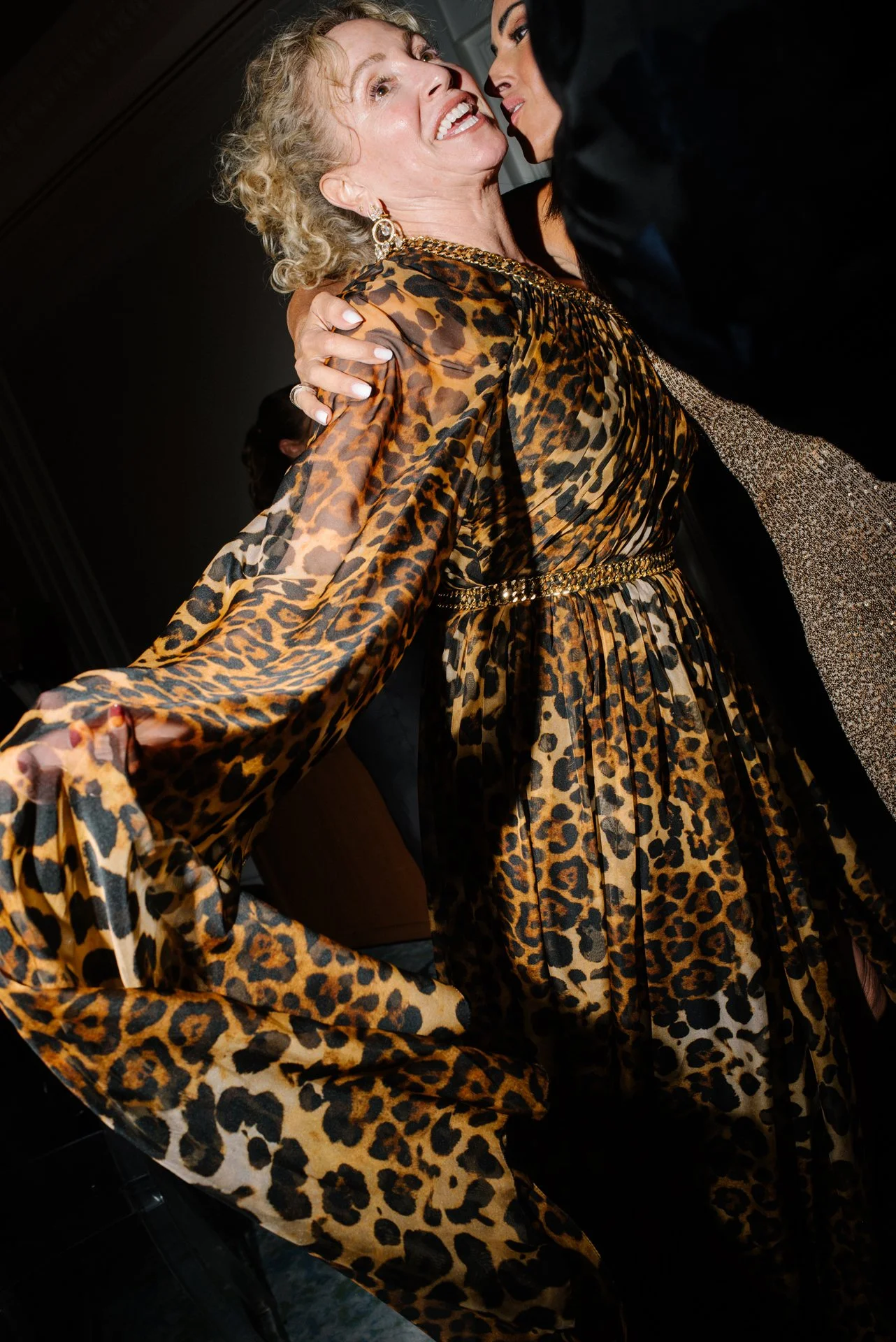 A woman in a leopard print dress holding her sleeves out.