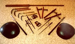 A collection of fitness equipment including two black aerobic balls, wooden sticks, a kettlebell, and other small fitness tools arranged on a yellow surface.