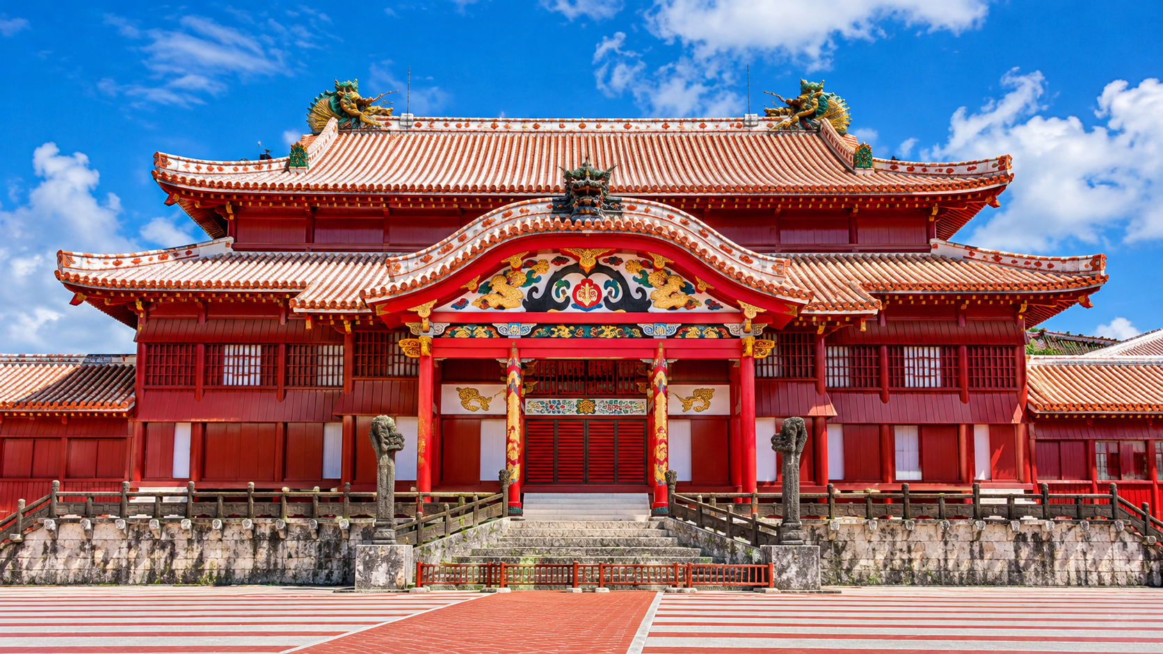Traditional Asian temple with red wooden structure, ornate decorations, and a tiled roof against a blue sky.