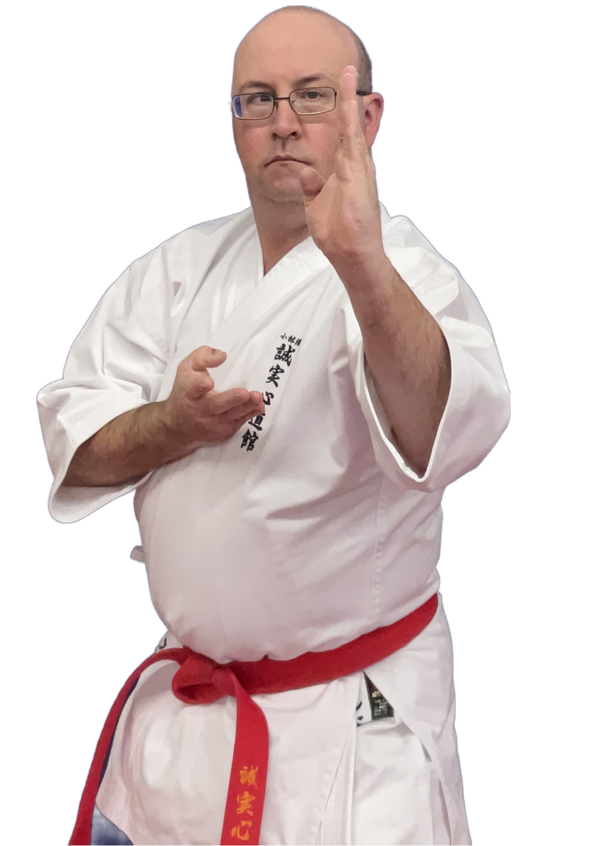 A man dressed in a white martial arts gi with a red belt, performing a martial arts move with a focused expression on his face.