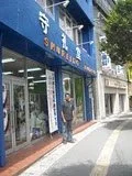 A person standing outside a store on a city sidewalk.