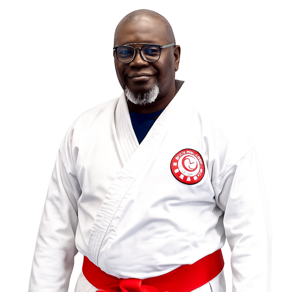 A man wearing a white martial arts uniform with a red belt and a patch on his chest, smiling and wearing glasses.