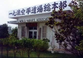Building with a sign reading 'Nishin-cho World Karate Association' and trees in front.