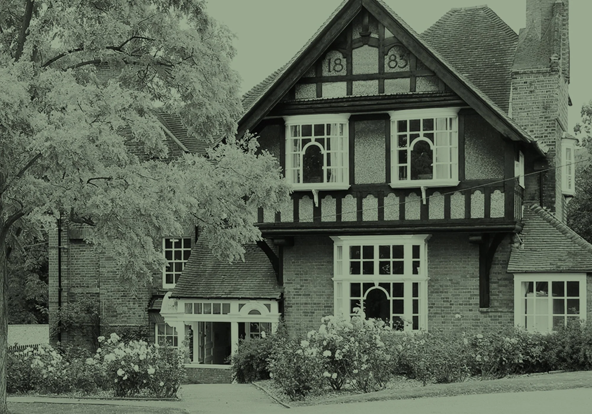 A vintage-style house with a decorative gable marked with the year 1888, surrounded by lush greenery and flowers.