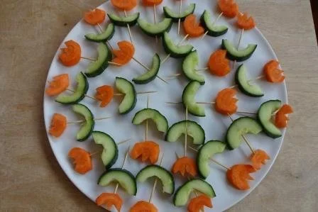 Kleine Snack-Spieße mit Gurke und Karotte auf einem weißen Teller