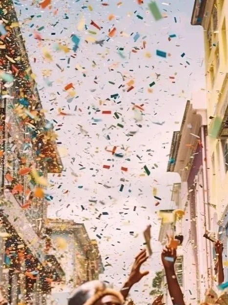 People celebrating with colorful confetti falling from the sky in a city street.