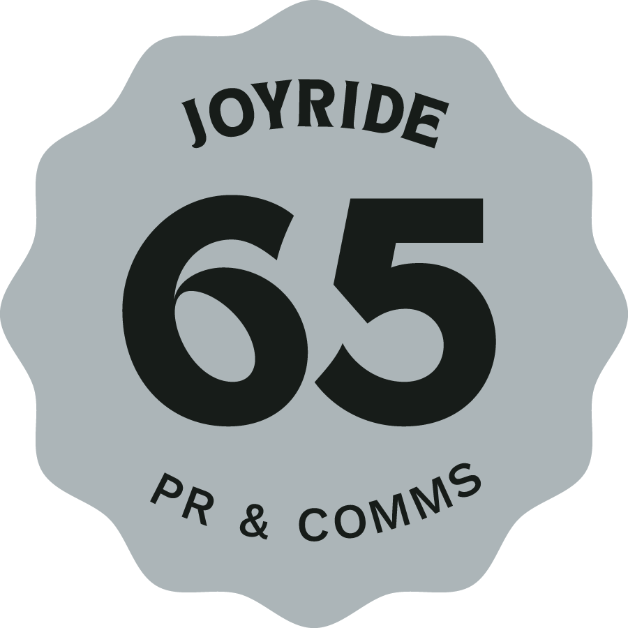 A graphic badge with a wavy border, displaying the text 'Joyride' at the top, a large number '65' in the center, and 'PR & Comms' at the bottom.