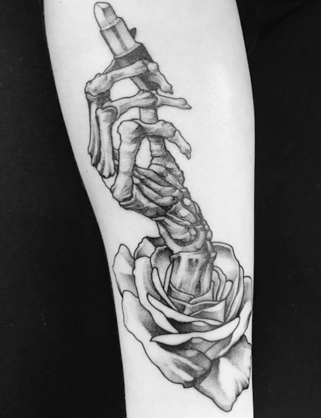 Black and grey skeleton hand holding rose tattoo by Gonzalo Chavez⁠