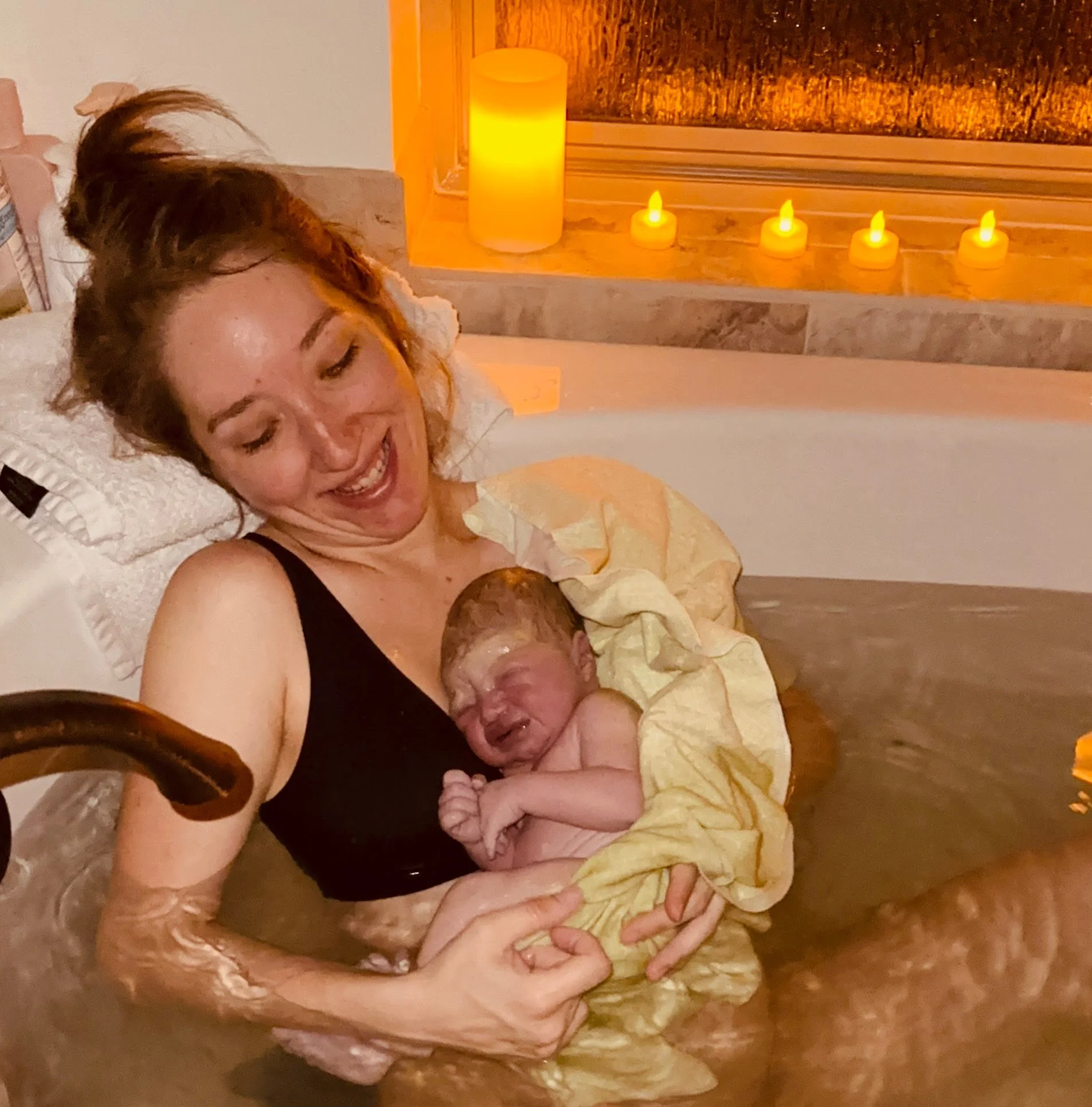 pregnant woman, homebirth, laboring and contracting in bathtub, baby born, cradling baby in bath, after birth, warm background, dim candles.