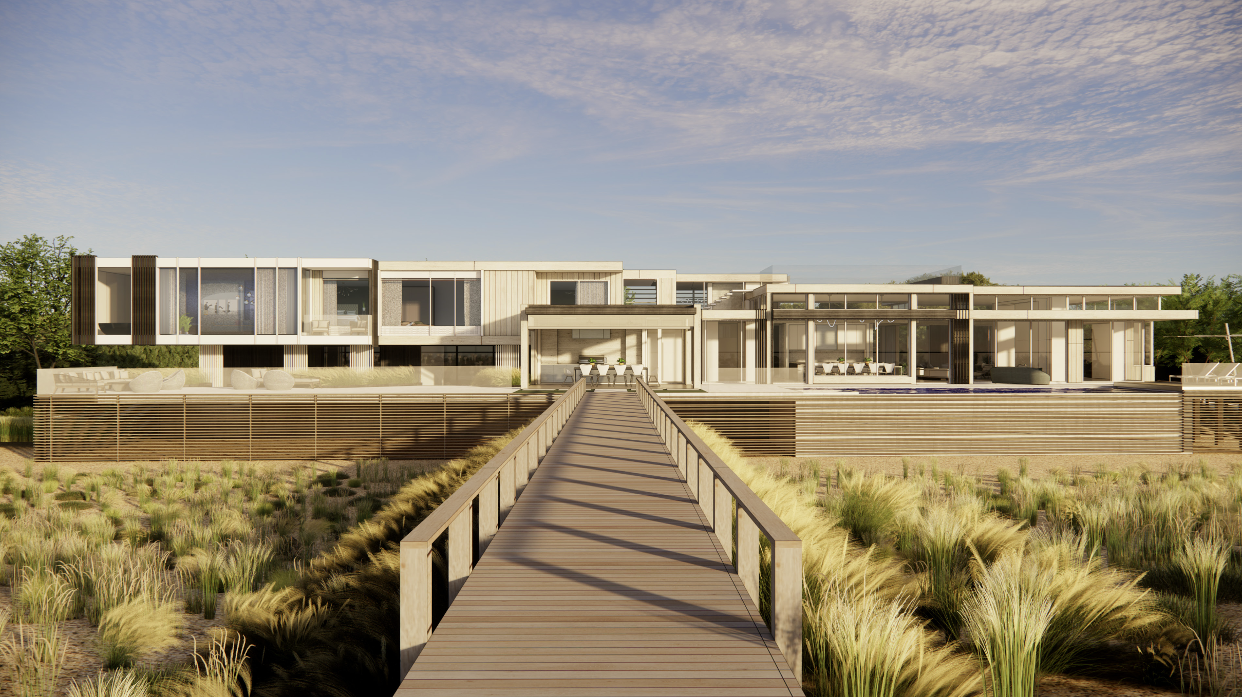 Modern beachfront house with a wooden pier leading to the entrance, surrounded by grassy dunes and trees, under a partly cloudy sky.