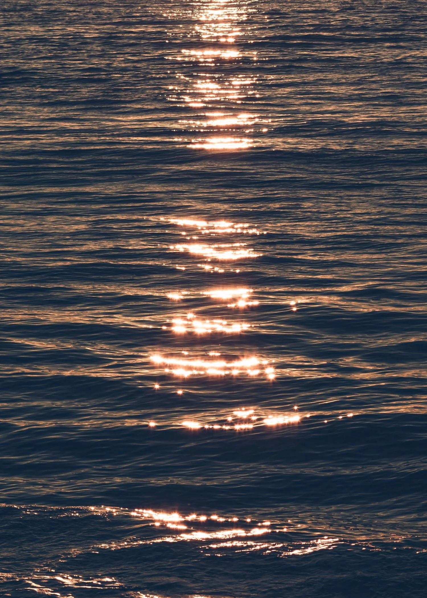 Sunlight reflecting off the surface of rippling water, creating sparkling highlights.
