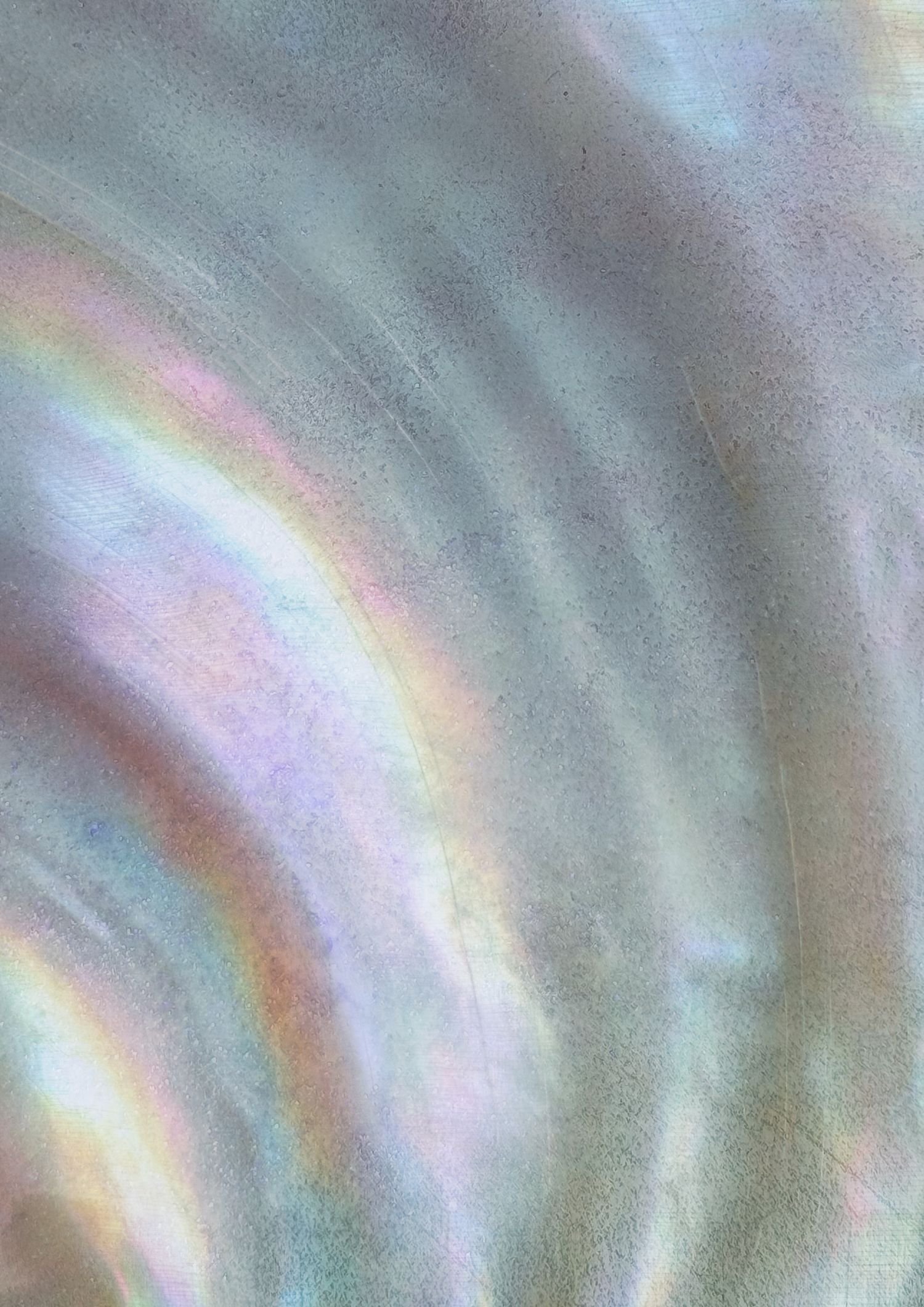 Close-up of iridescent, metallic surface with rainbow-like colors and a textured finish.