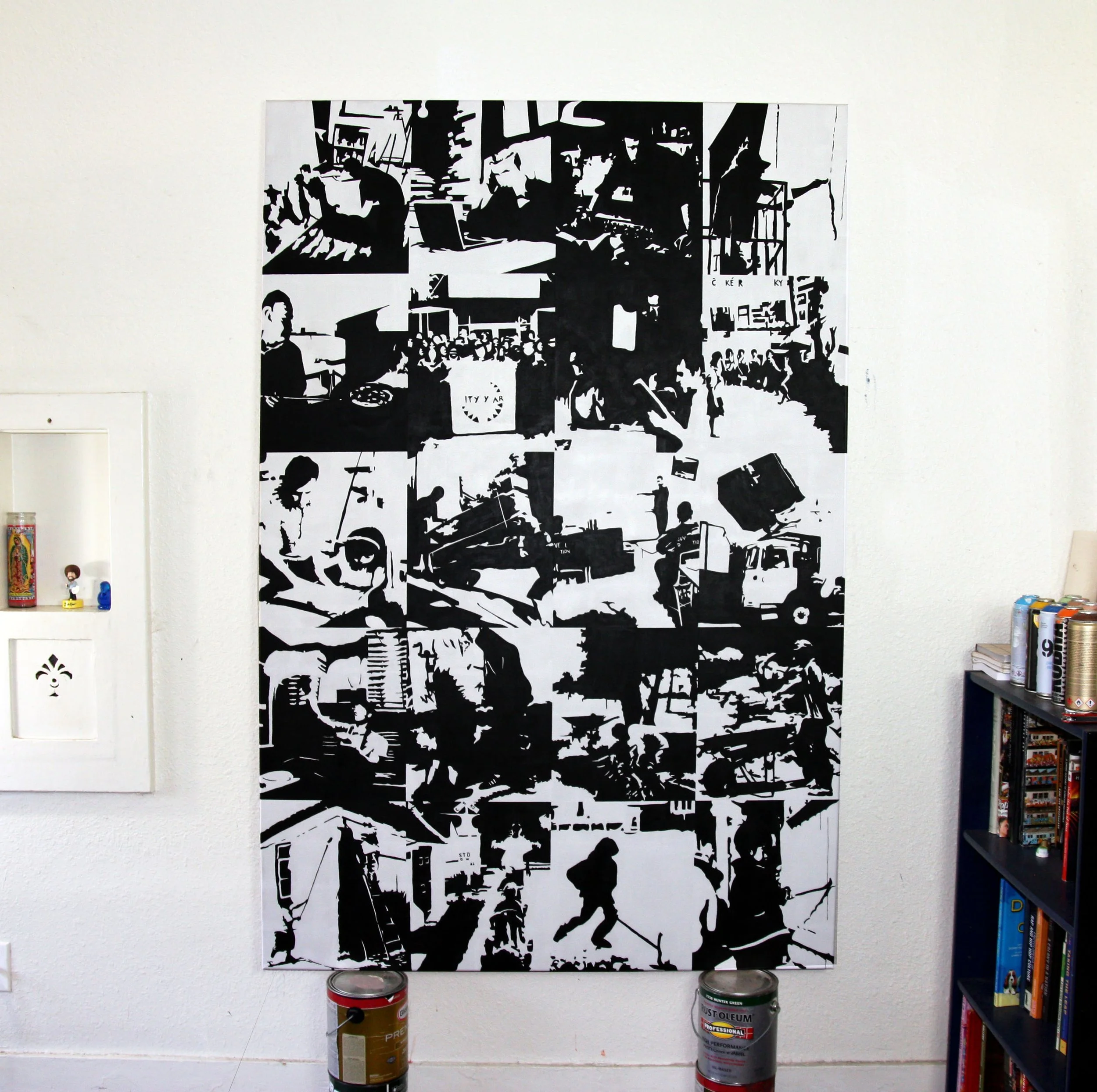 Black and white abstract art piece in a gallery, surrounded by white wall, with cans of paint at the bottom.
