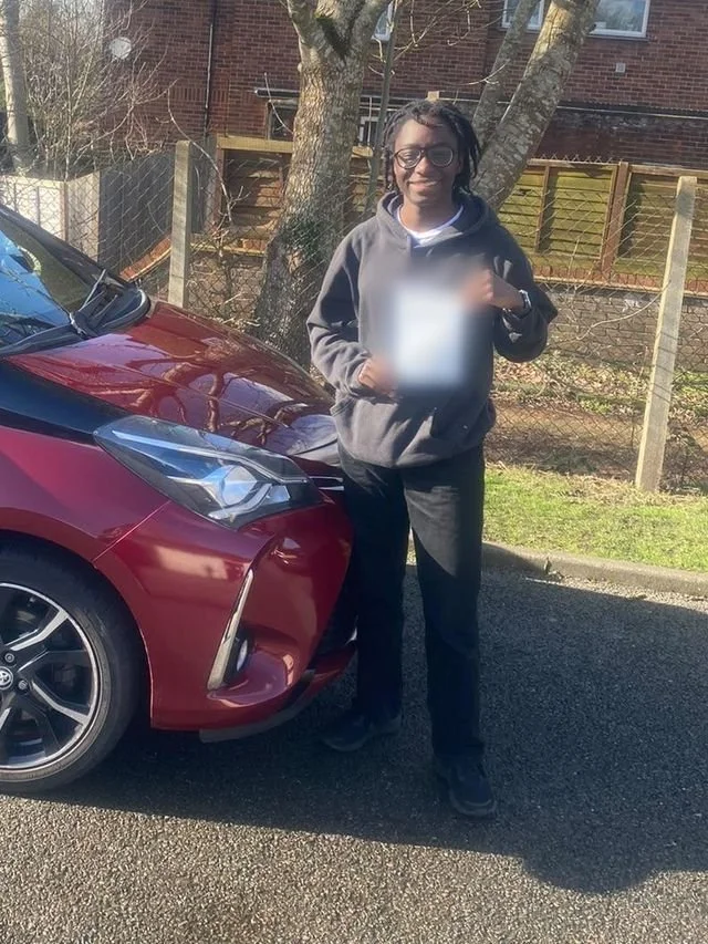 A student holding their driving test pass certificate beside the red Toyota Yaris