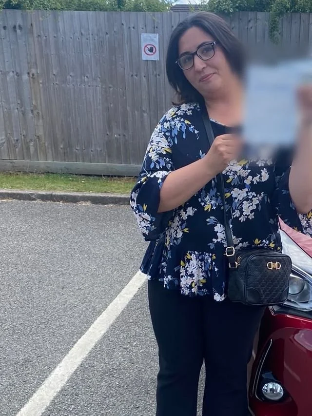 A student holding their driving test pass certificate beside the red Toyota Yaris