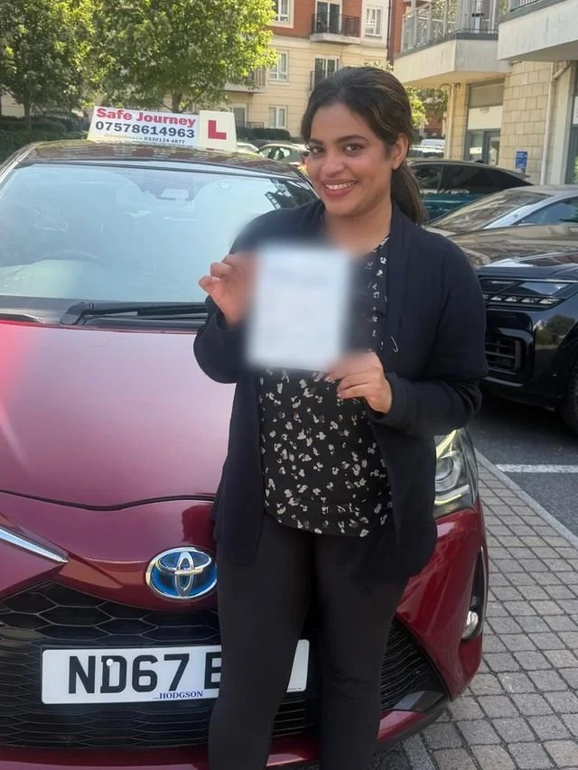 A student holding their driving test pass certificate beside the red Toyota Yaris