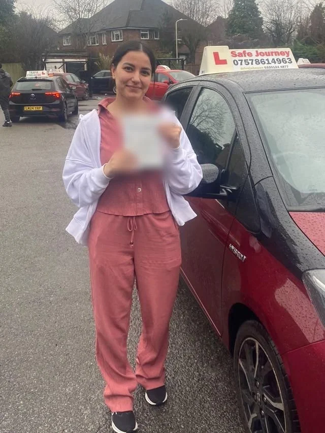 A student holding their driving test pass certificate beside the red Toyota Yaris