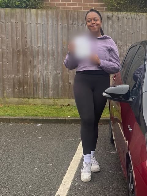 A student holding their driving test pass certificate beside the red Toyota Yaris