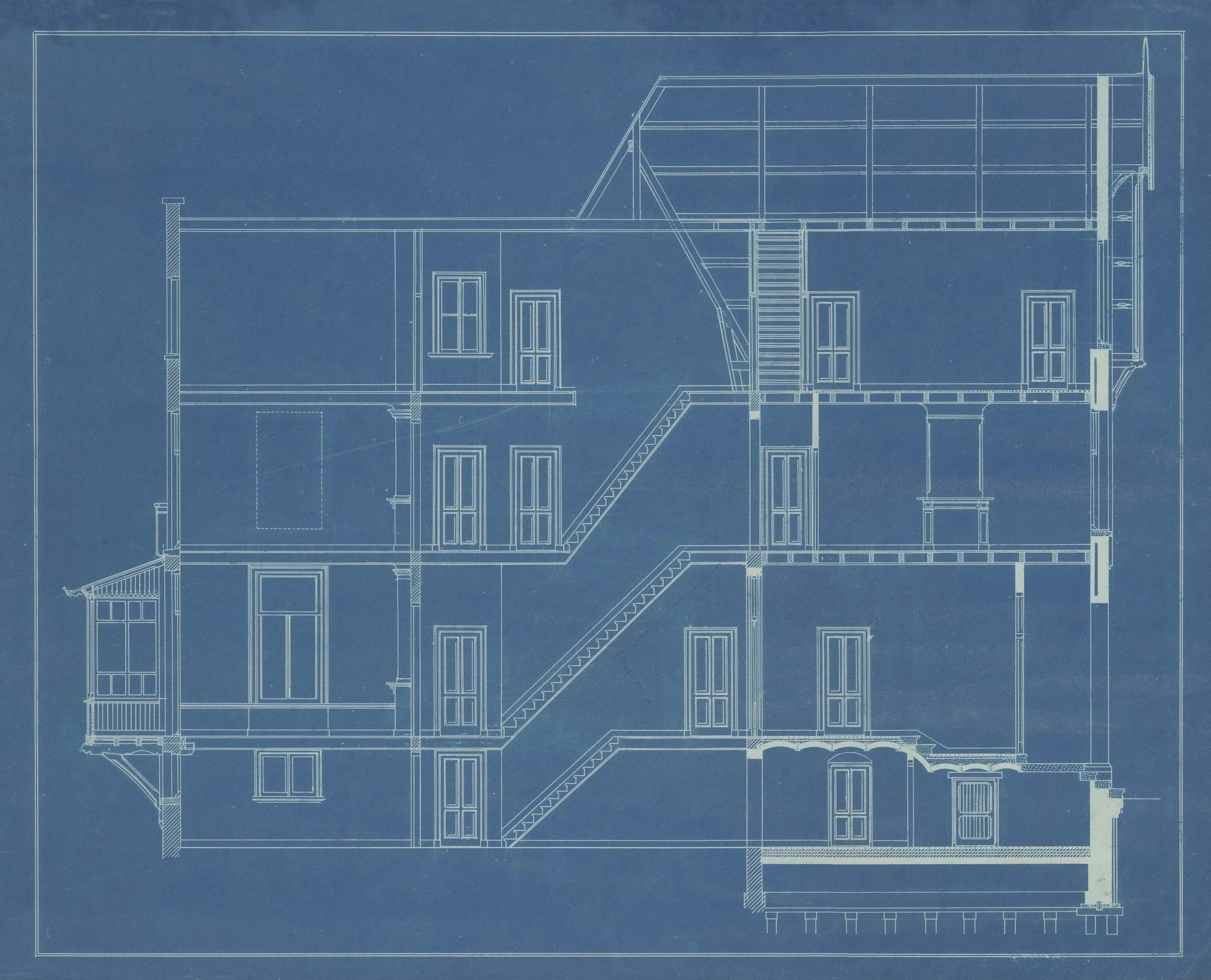 Blueprint of a multi-story house with interior details like stairs, windows, and rooms outlined in white lines on a blue background.