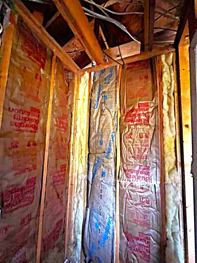 Interior of a wall under construction with wooden studs and insulation panels.