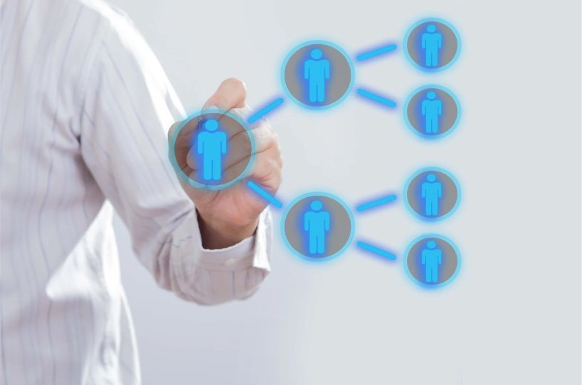Person in a white shirt pointing at a virtual diagram of connected human icons in blue, representing network or relationship concept