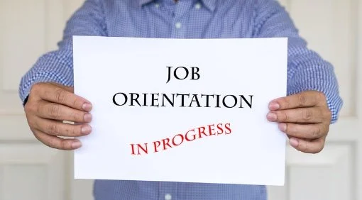 Person holding a sign that says 'Job Orientation' with 'In Progress' written below in red