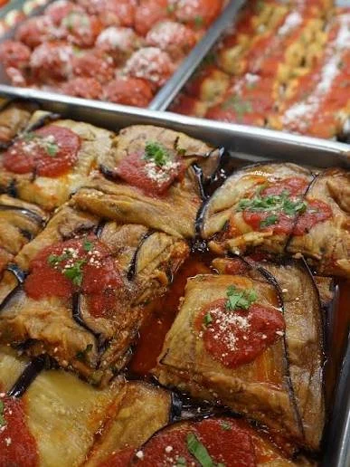 Baked eggplant parmesan with tomato sauce and herbs in a baking dish.