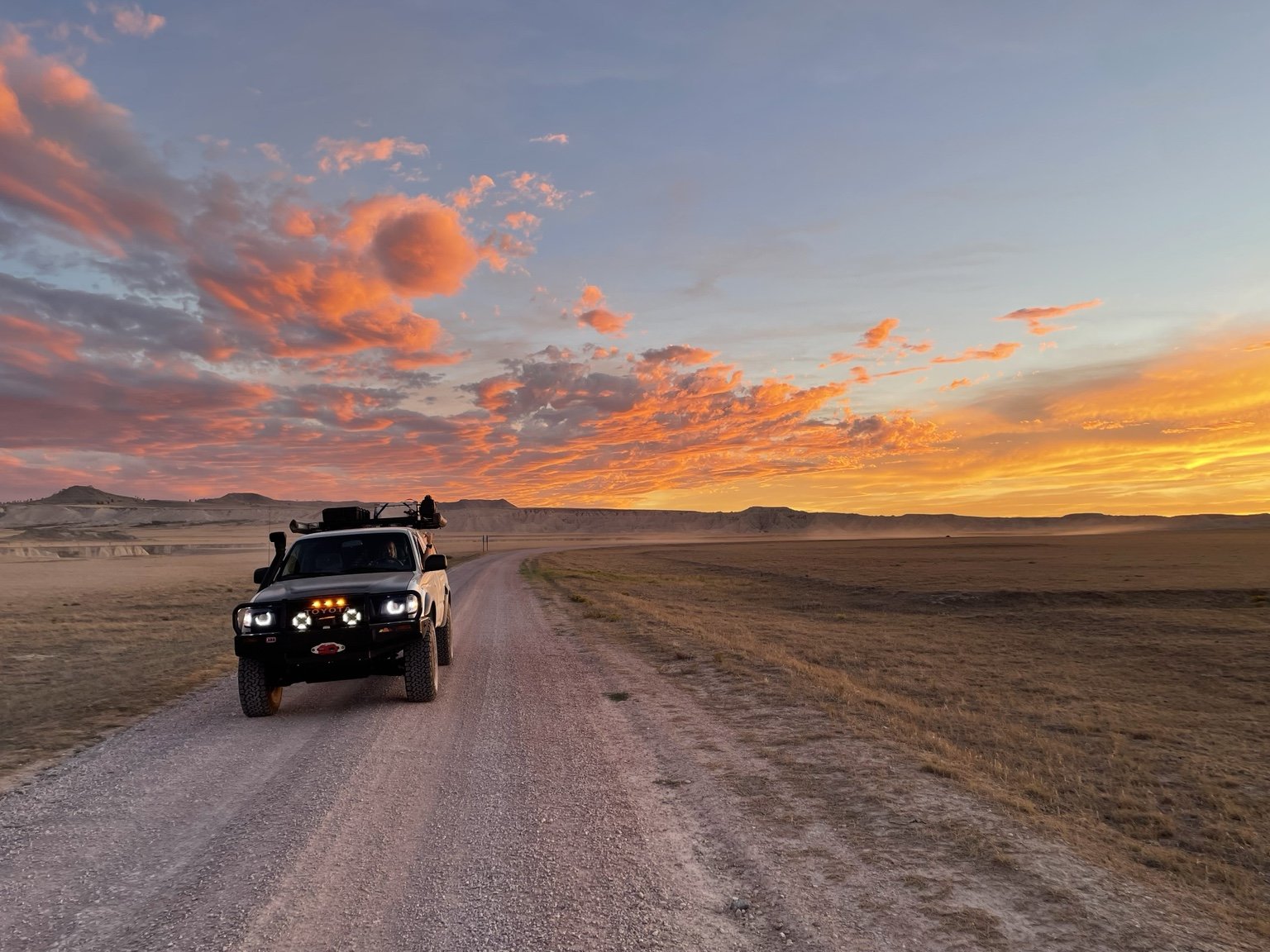 Randy’s Toyota Tacoma, Strider, on a gravel road beneath a vivid orange sunset.