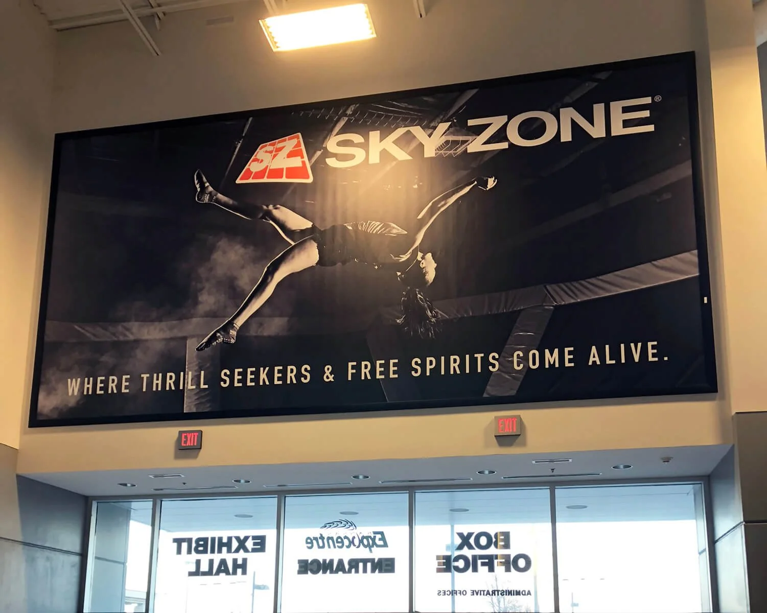 Large advertisement for Sky Zone trampoline park showing a person mid-air doing a flip. The text reads, 'Where thrill seekers & free spirits come alive.'