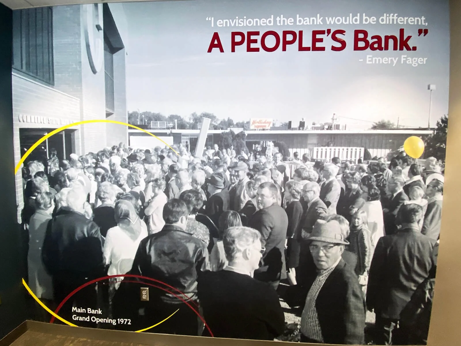 Black and white photo showing a large crowd of people gathered outside a building, likely for a grand opening event in 1972. The building has a sign reading "Main Bank". A quote at the top right says, 'I envisioned the bank would be different, A PEOP