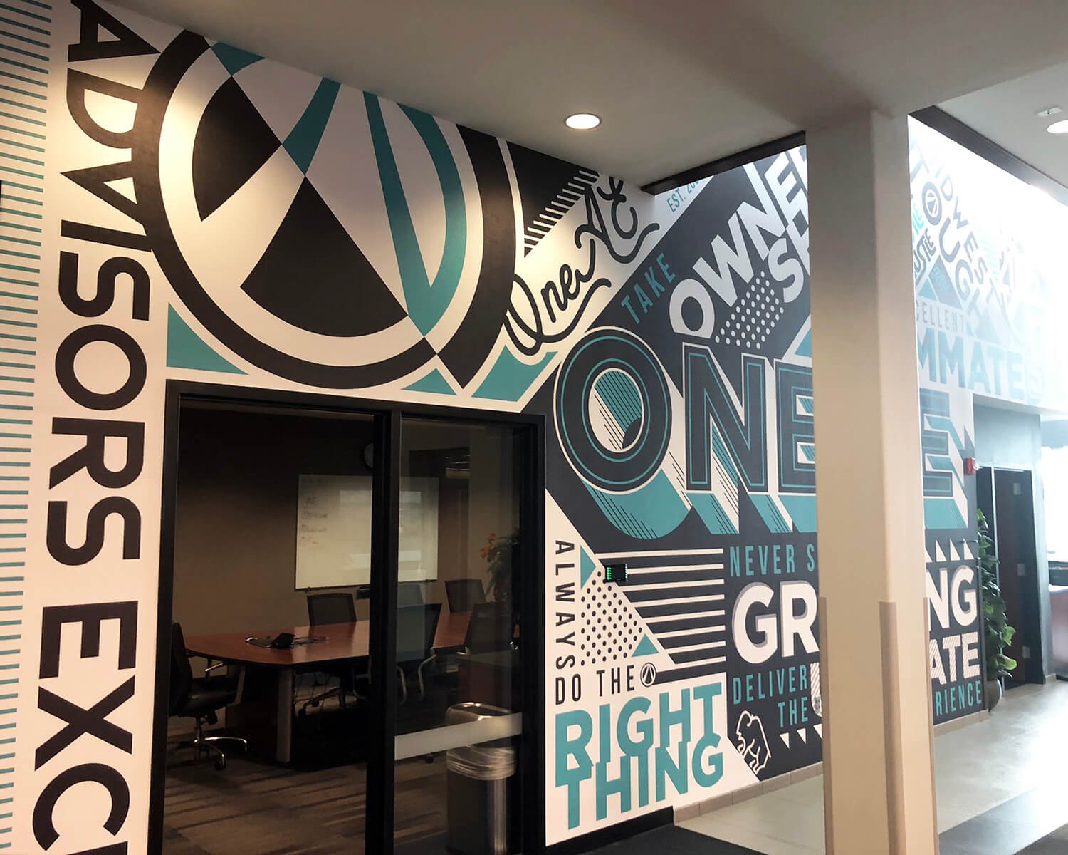 Colorful motivational wall art with words like "One," "Rights," "Always," "Do the right thing," and "Never give up" in a modern office building hallway.
