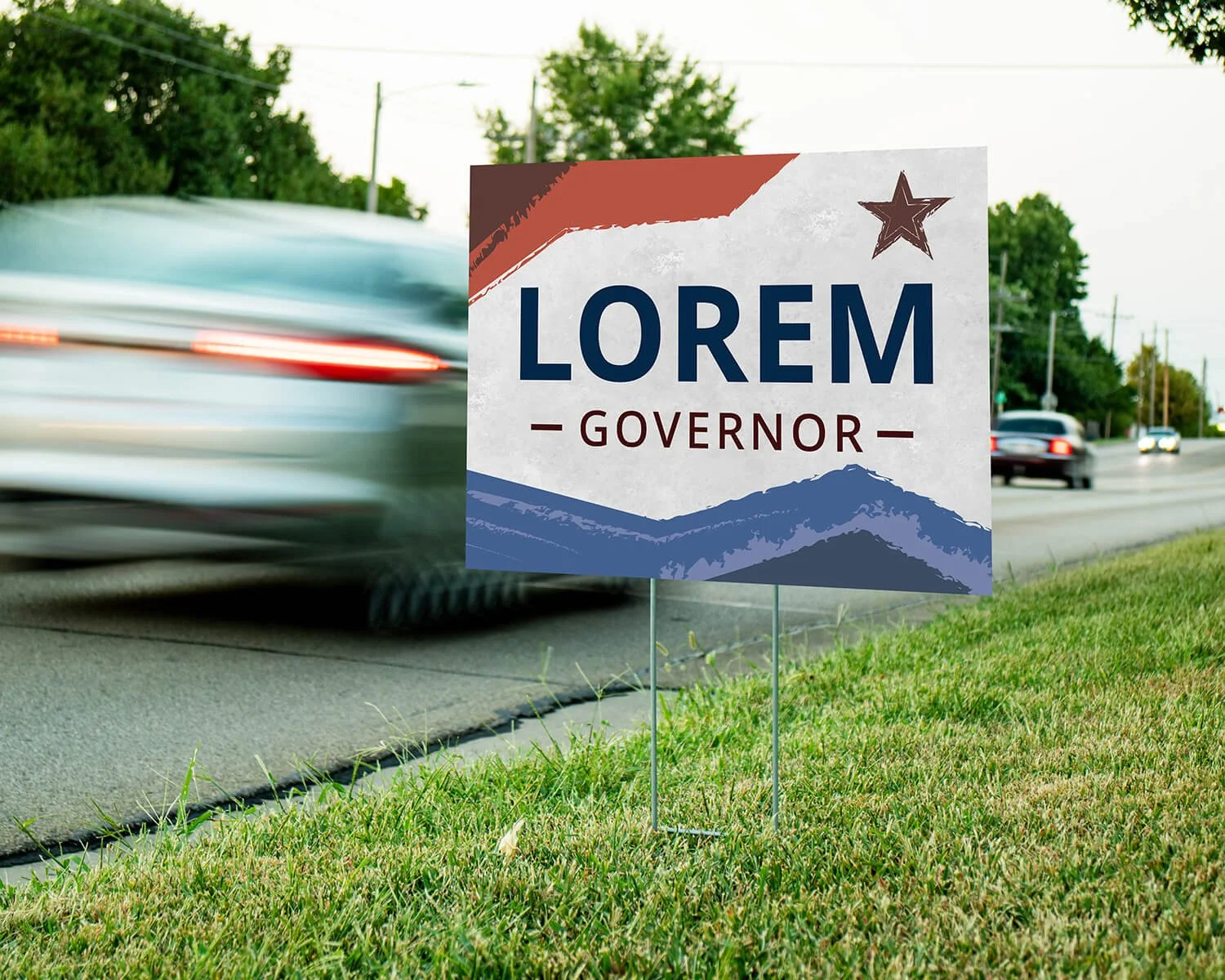 Political campaign sign that reads "LOREM GOVERNOR" with a mountain illustration at the bottom and a star at the top right corner, placed by the side of a busy road while cars pass nearby.