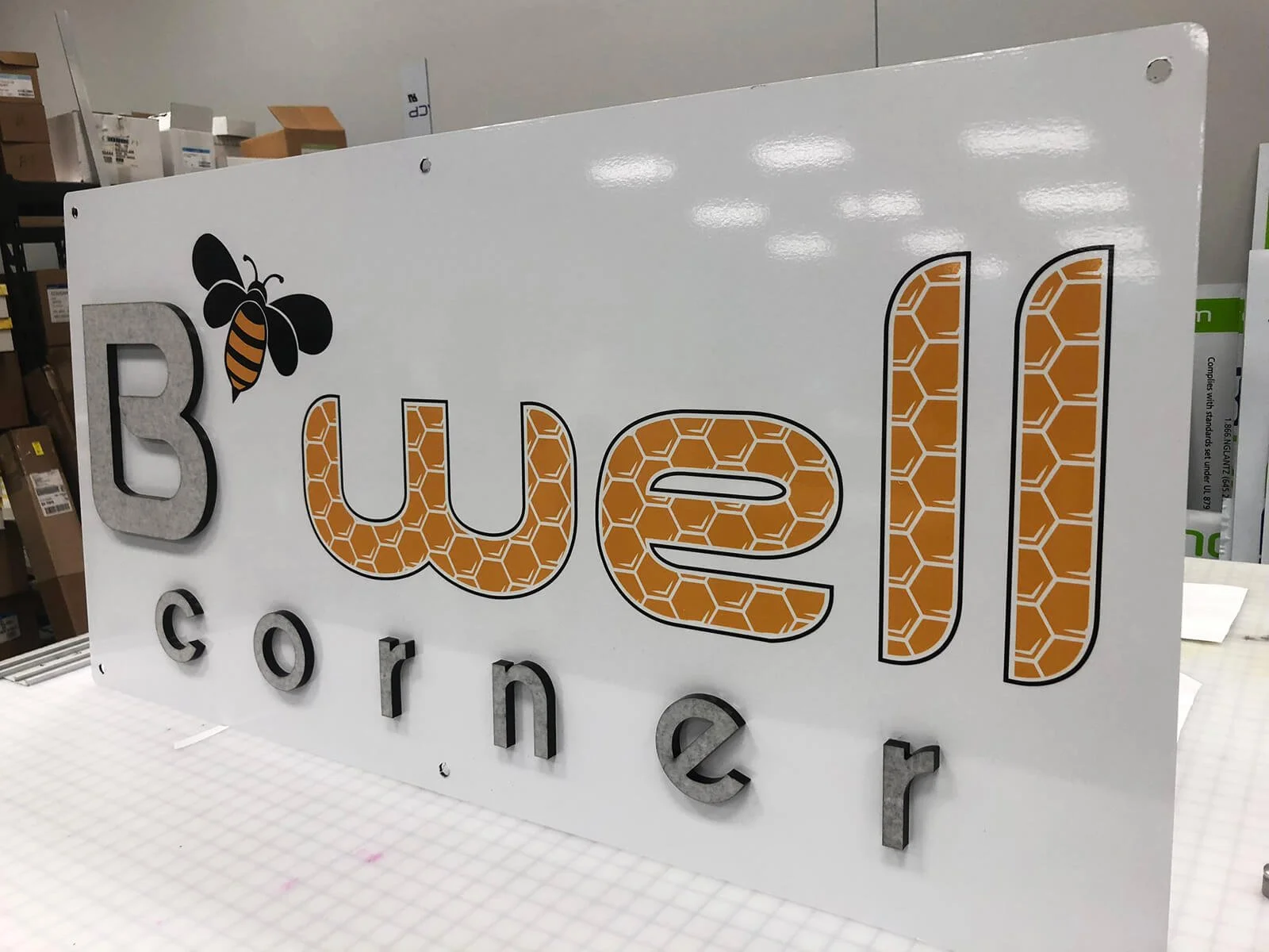 Sign with the words "B WELL CORNER" and a bee graphic, with the word 'corner' in lowercase letters.
