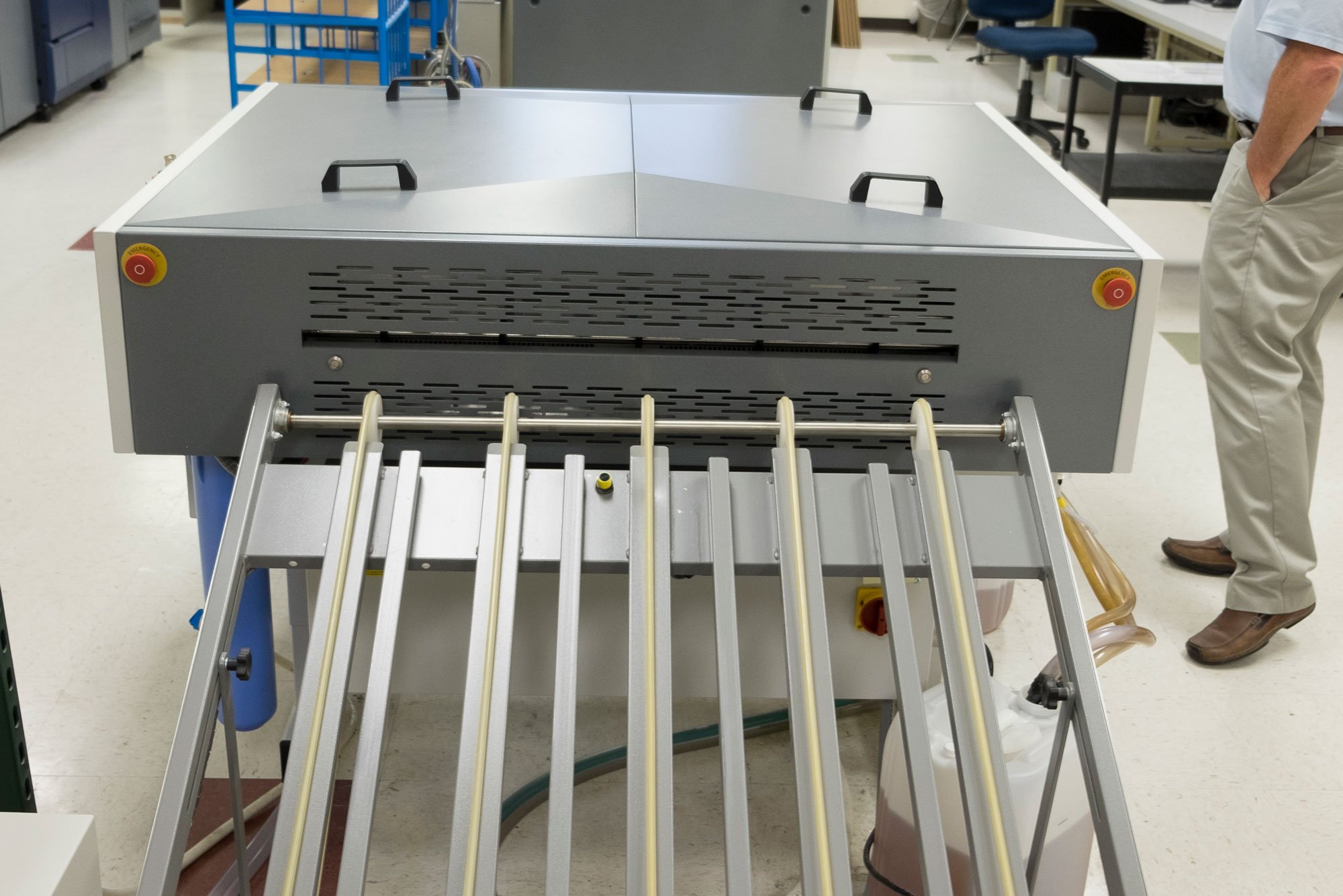 Industrial machine with multiple rollers in a print shop setting.