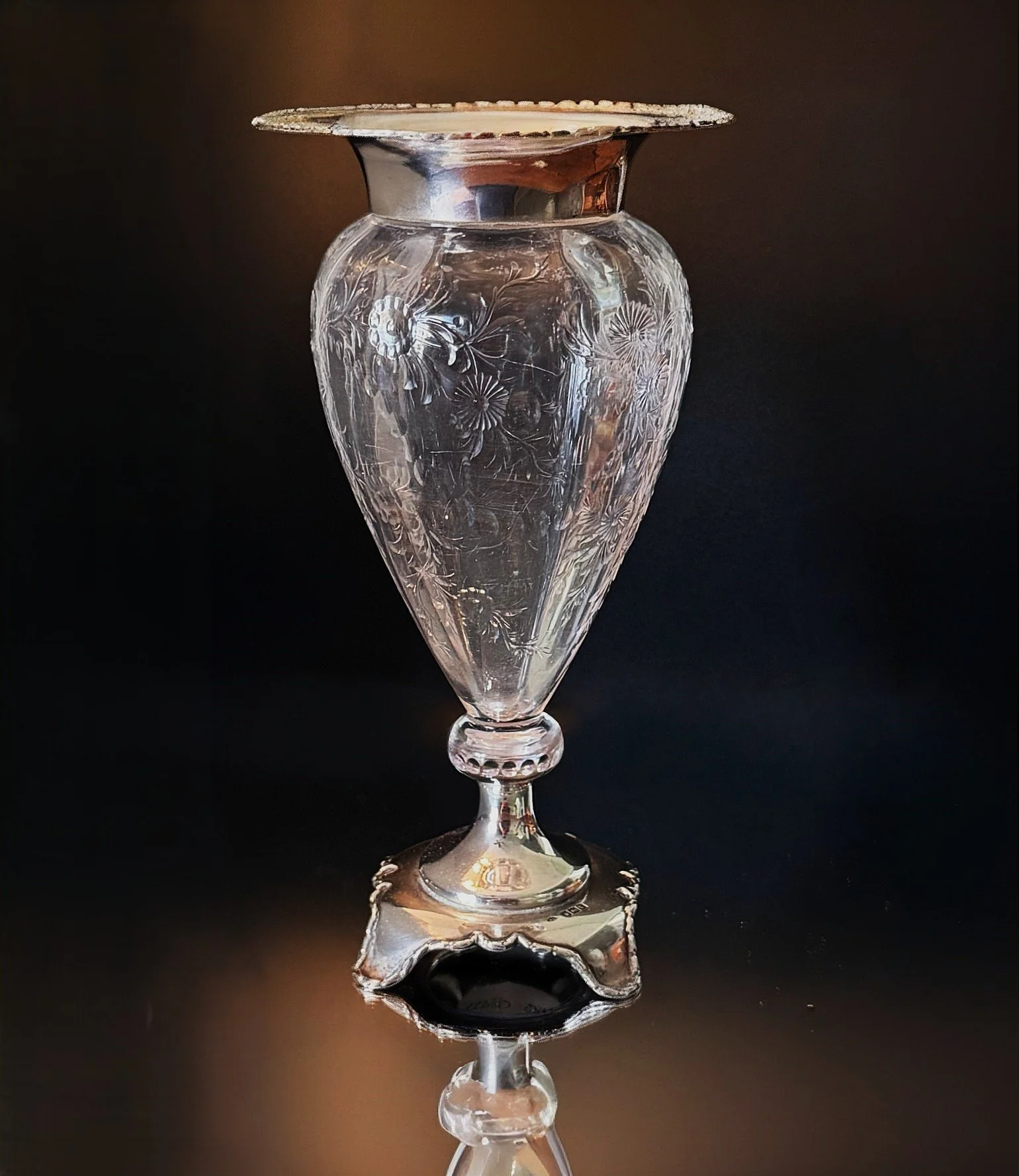 A clear, intricately etched glass vase with floral patterns.