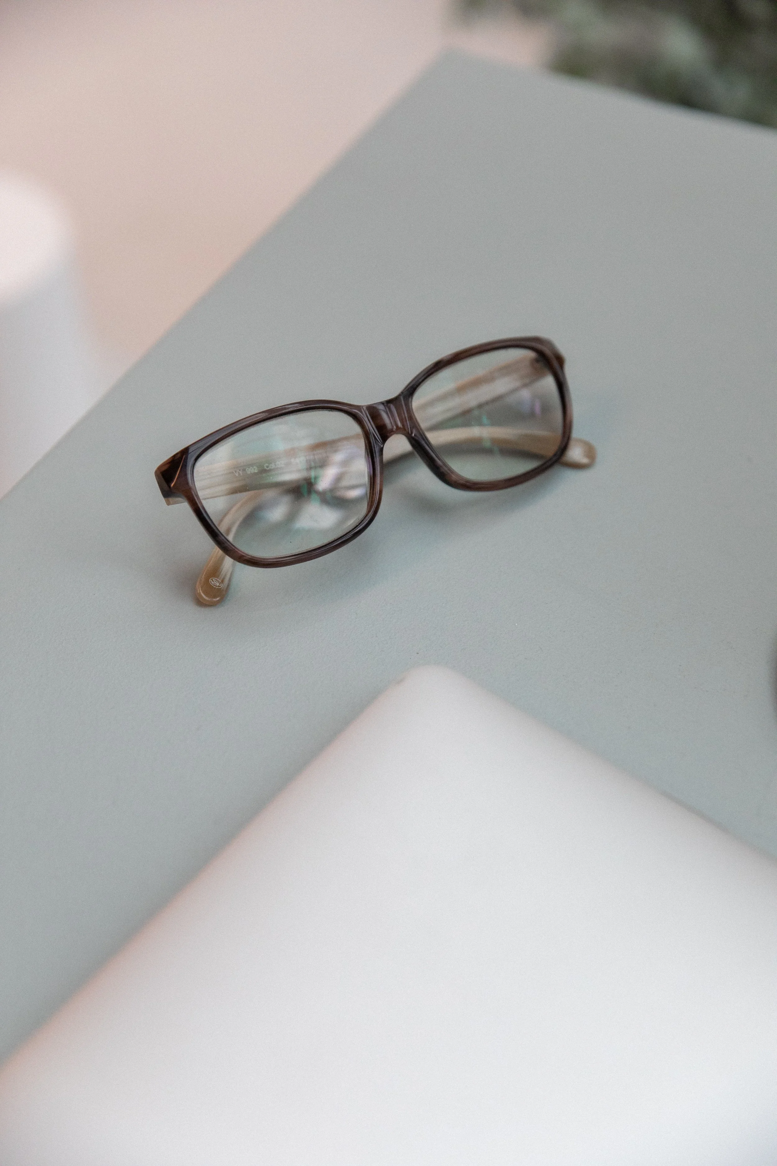 Brown eyeglasses resting on a light blue and white surface.