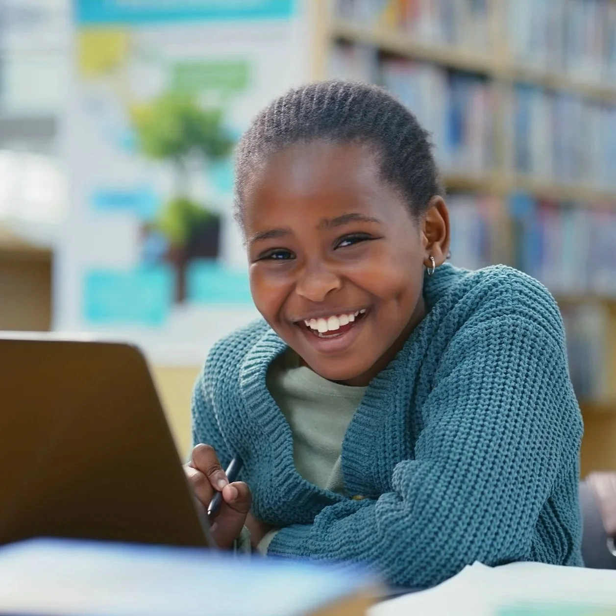 A young girl smiling while using a tablet in a library.