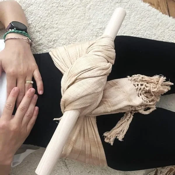 Resserage de bassin avec le rebozo, maintenu avec un baton en bois. Rebozo, tissu traditionnel mexicain, couleur rose pâle.