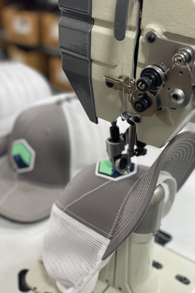 A sewing machine stitching fabric on a textile production line in a factory.