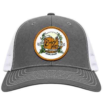 Gray and white trucker hat with a patch of a beer mug on the front, decorated with green hops and a banner that reads "Edy Zone," with the location "Boise, Idaho."