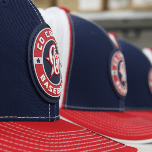 Several navy blue and red baseball caps with a logo that says 'Colo Co Baseball' and features a baseball and a star.