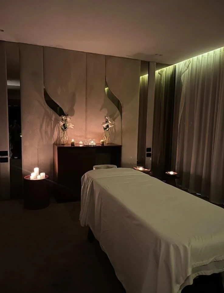 Spa room with a massage bed, candles, and elegant decor.