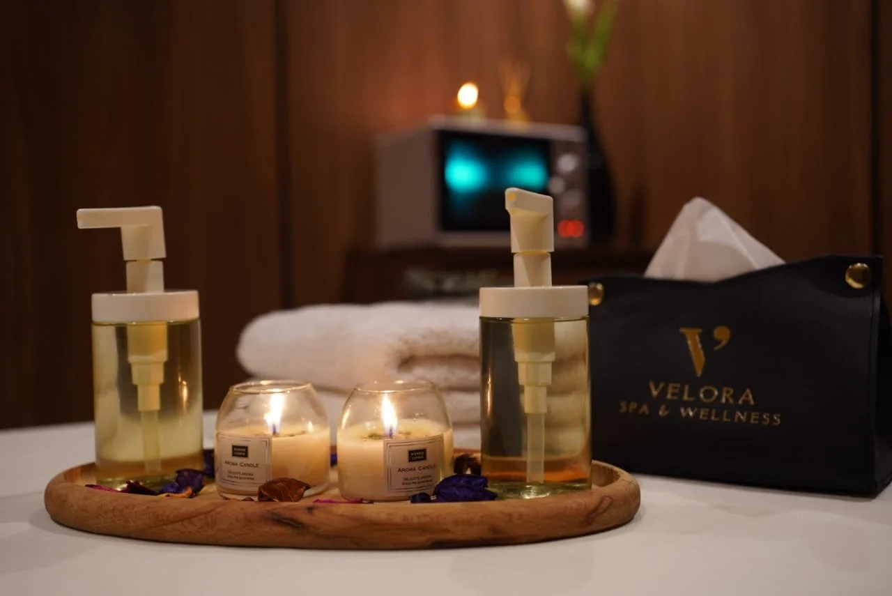 Spa setting with candles, lotion bottles, towel, and Spa & Wellness bag on a white table