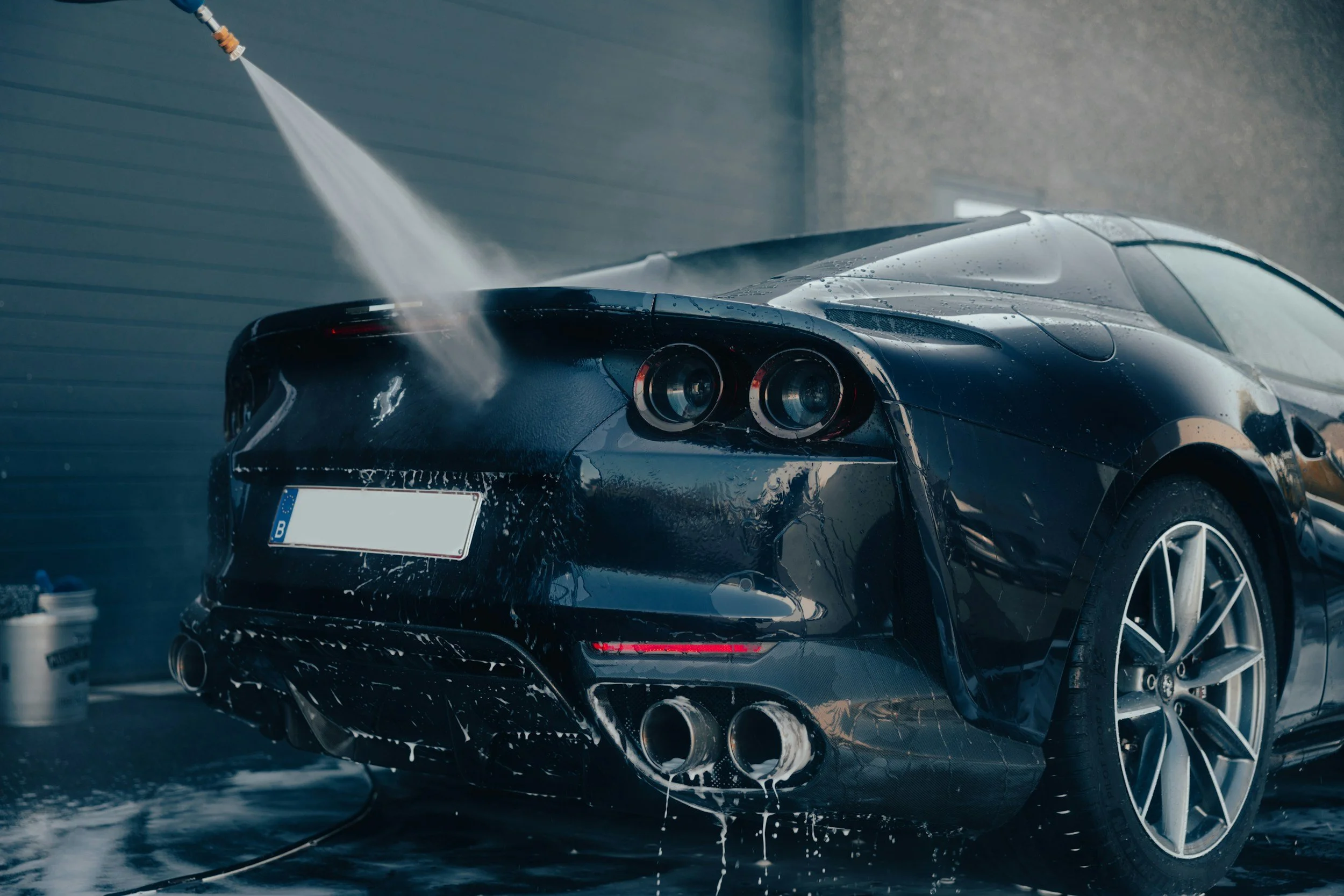 A black sports car being washed in a car wash station.
