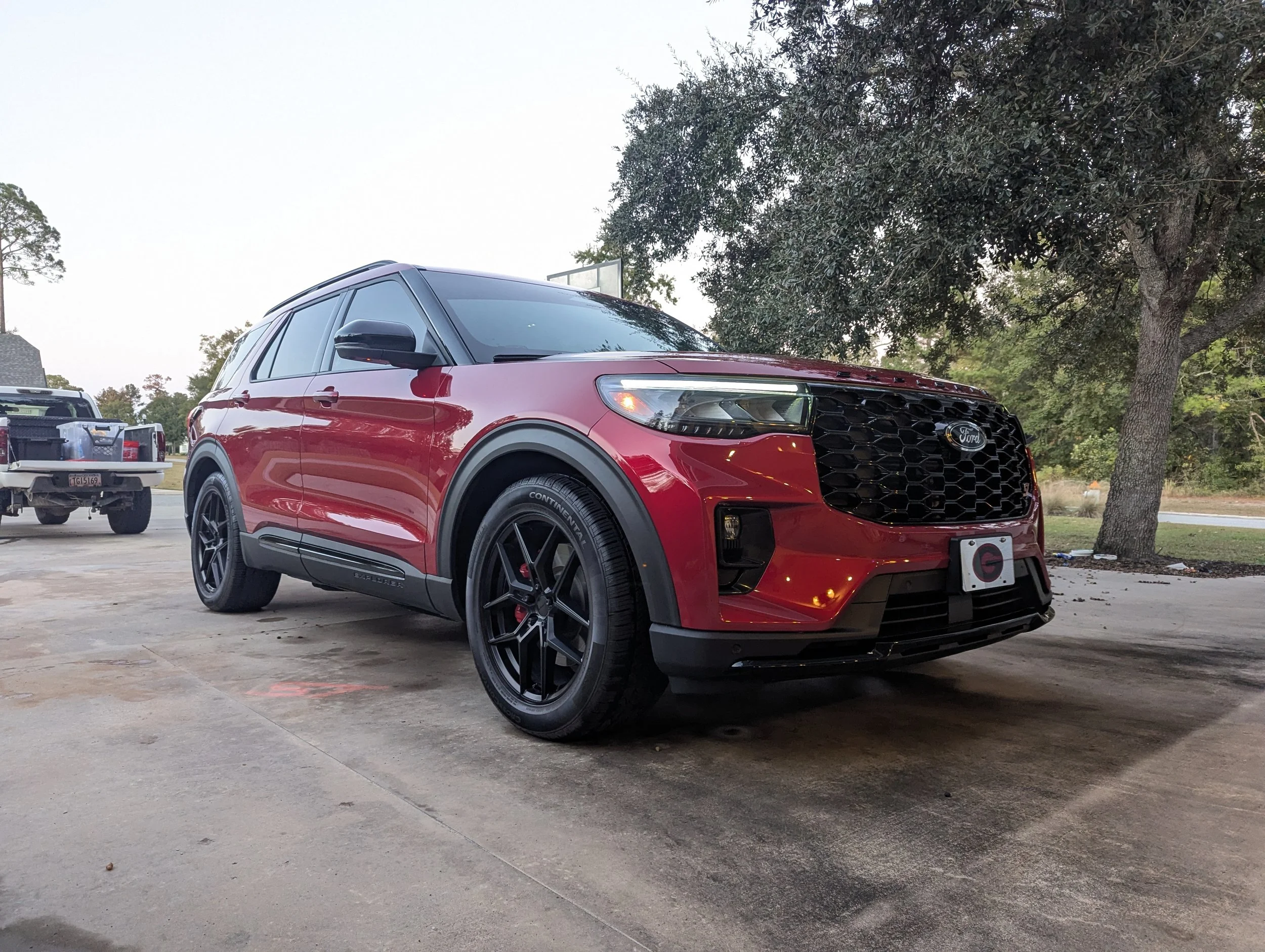 A red Ford SUV parked outdoors near trees and other vehicles, with a clear sky overhead.