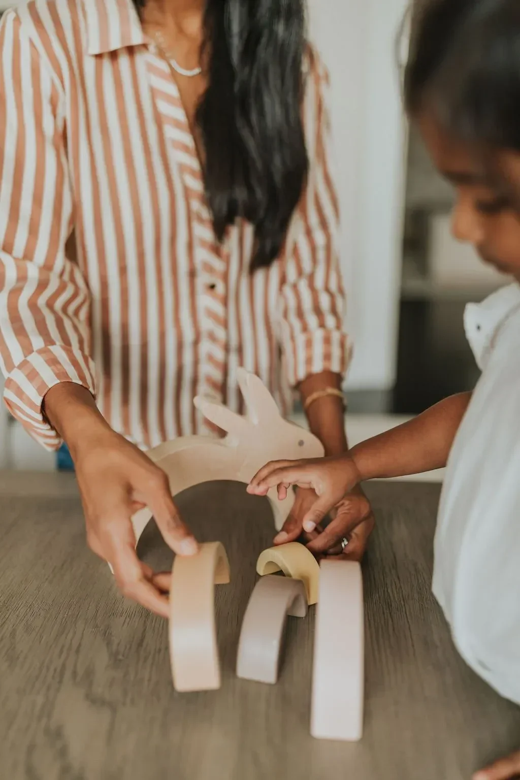 Two people assembling a wooden toy on a table