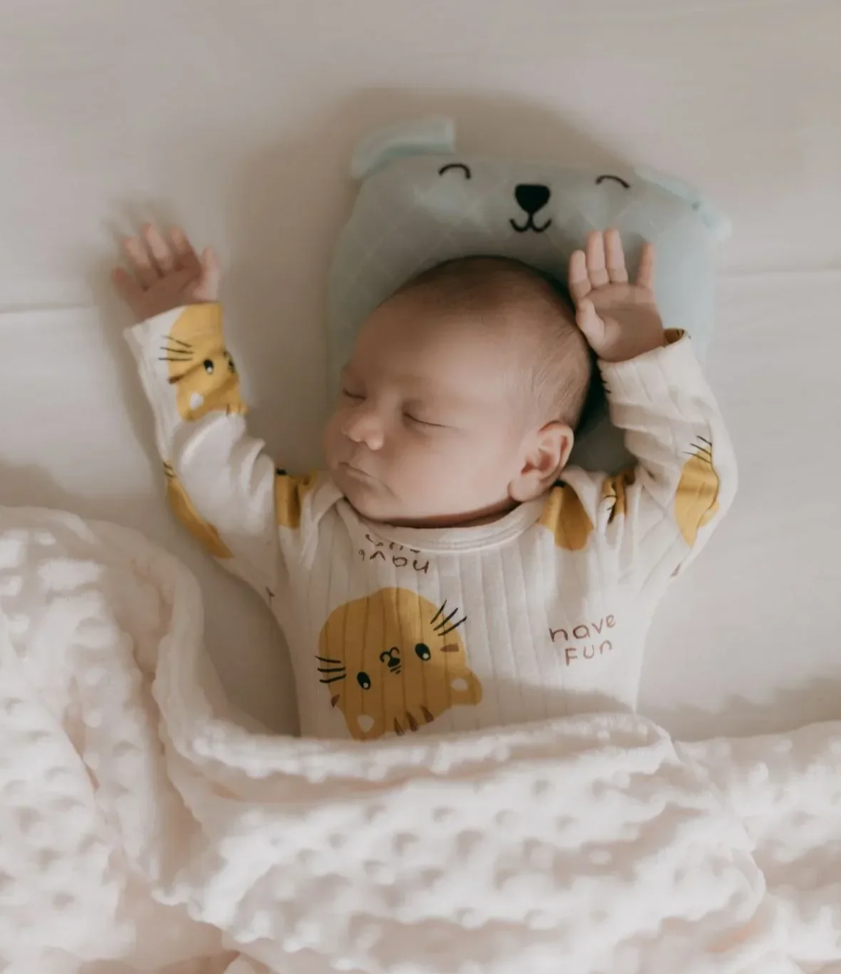 Sleeping newborn baby in a white and mustard-yellow animal-print outfit