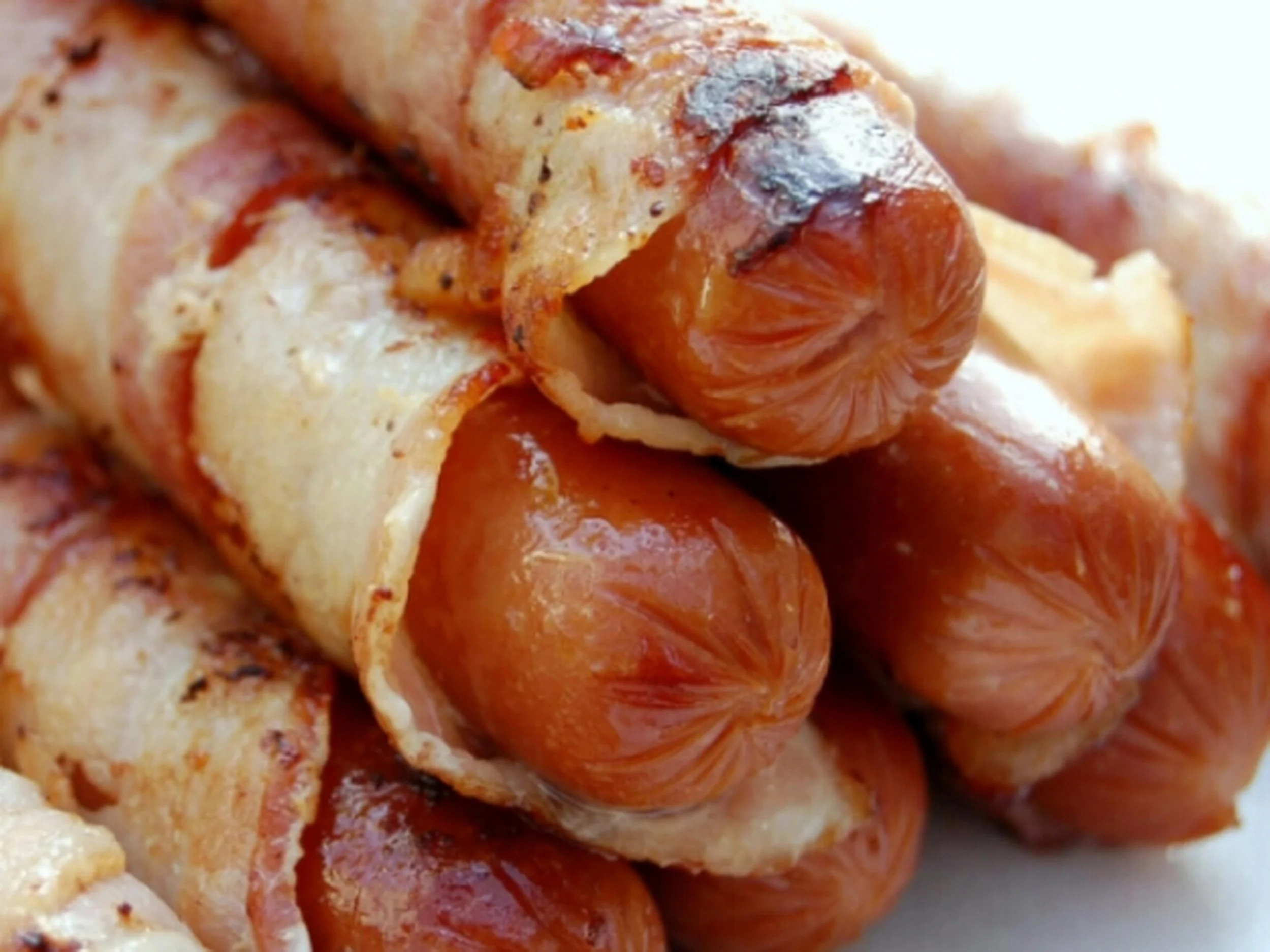 Close-up of cooked bacon-wrapped chicken pieces.