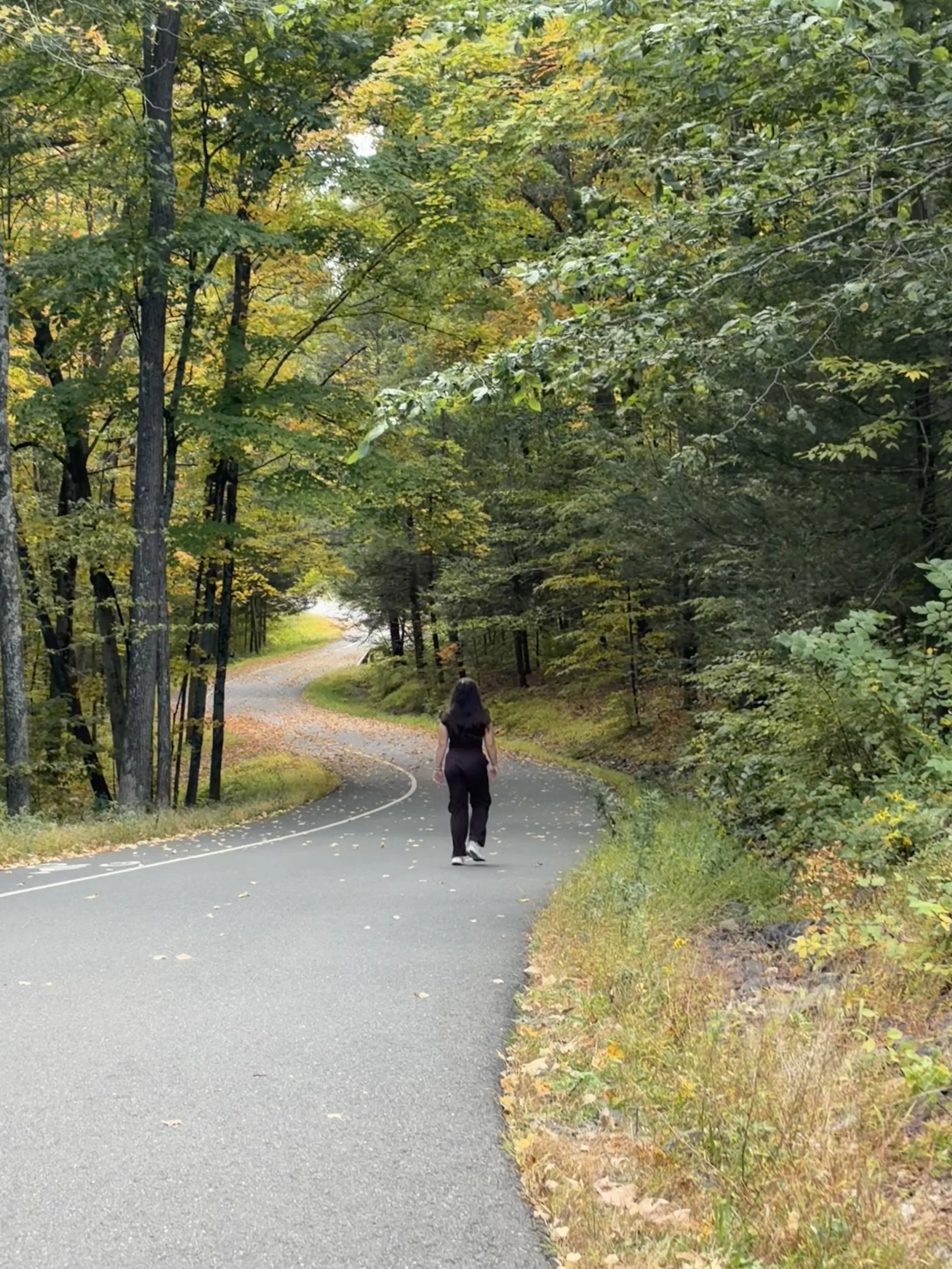 Amber walking along a wooded road for walk-and-talk therapy in Connecticut.